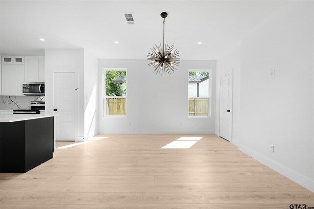 unfurnished dining area featuring an inviting chandelier and light hardwood / wood-style flooring