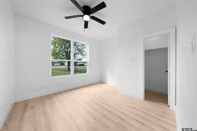 unfurnished bedroom featuring a closet, ceiling fan, a spacious closet, and light hardwood / wood-style floors