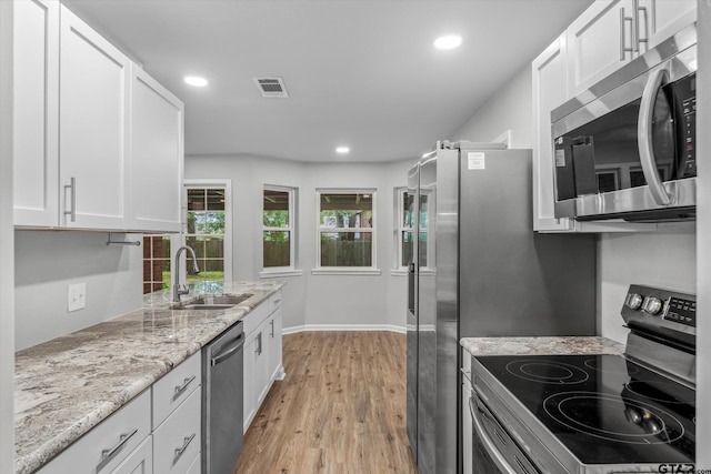 1004 Bunny Rabbit Rd, Athens, TX 75751 - kitchen with stainless steel appliances, white cabinets, light wood-type flooring, recessed lighting, and light stone countertops