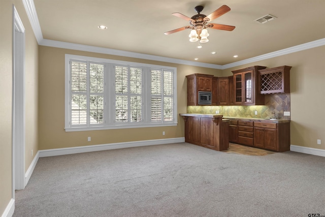 6805 Castle Pines Ct, Tyler, TX 75703 - kitchen featuring light carpet, stainless steel microwave, glass insert cabinets, crown molding, and recessed lighting