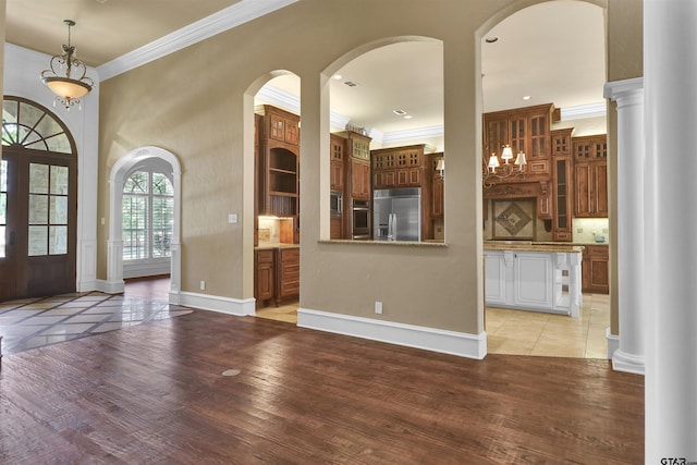 6805 Castle Pines Ct, Tyler, TX 75703 - entryway featuring crown molding, light wood-type flooring, baseboards, ornate columns, and arched walkways
