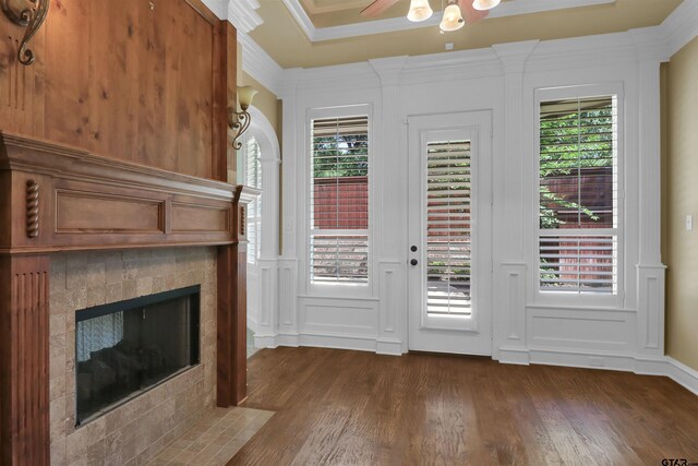 6805 Castle Pines Ct, Tyler, TX 75703 - entryway with a decorative wall, dark wood-style floors, a tiled fireplace, a ceiling fan, and crown molding