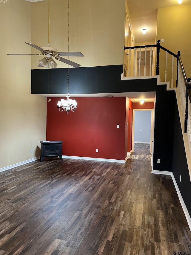 unfurnished living room with ceiling fan with notable chandelier, dark hardwood / wood-style floors, and a high ceiling