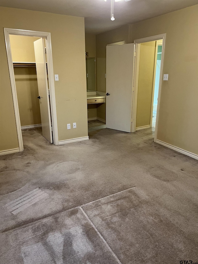 unfurnished bedroom featuring connected bathroom, a spacious closet, light colored carpet, and a closet