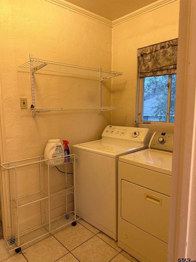 laundry area with washing machine and clothes dryer, light tile patterned floors, and crown molding