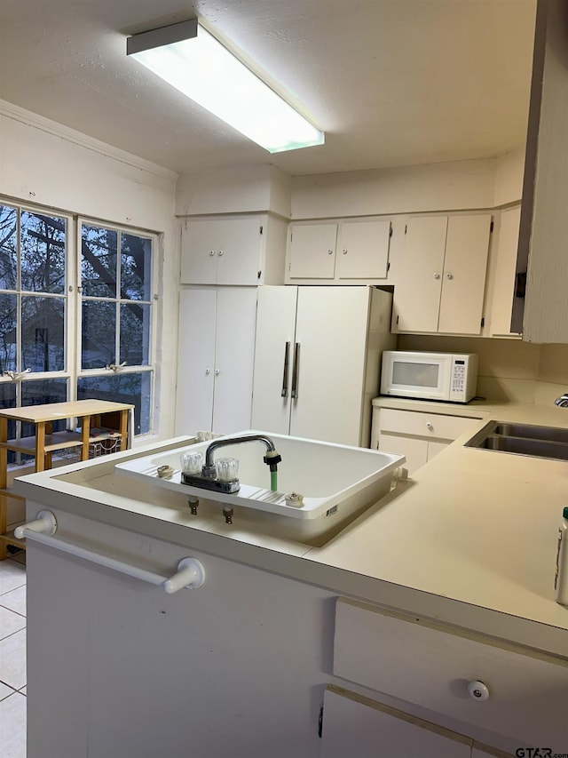 kitchen with white cabinets, sink, crown molding, and light tile patterned floors