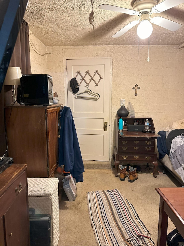 bedroom featuring a textured ceiling, light colored carpet, and ceiling fan