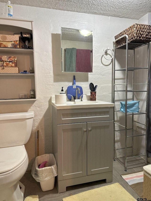 bathroom with vanity, a textured ceiling, and toilet