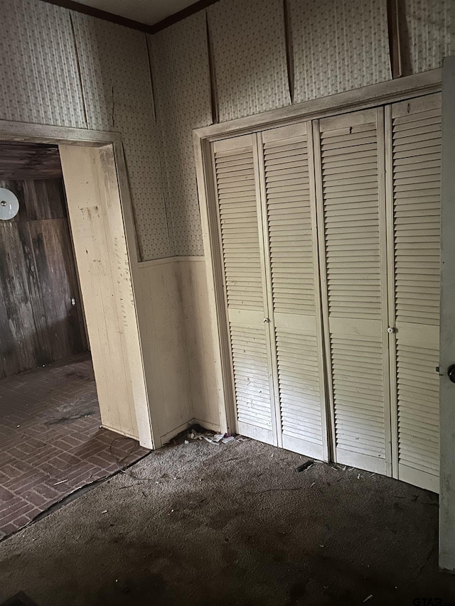 524 E San Antonio St, Alto, TX 75925 - unfurnished bedroom featuring a closet, wood walls, brick patterned floors, and a wainscoted wall