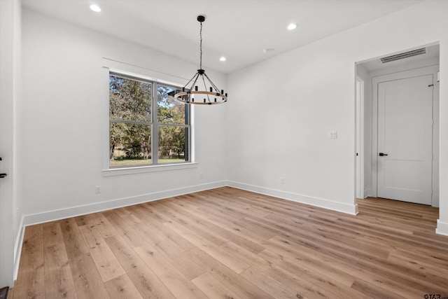 unfurnished dining area featuring light hardwood / wood-style floors and an inviting chandelier