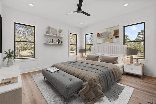 bedroom with multiple windows, light hardwood / wood-style floors, and ceiling fan