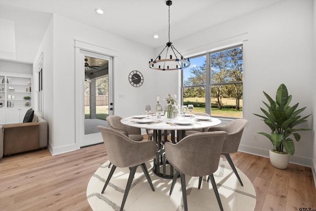 dining space with built in shelves, a healthy amount of sunlight, and light hardwood / wood-style flooring