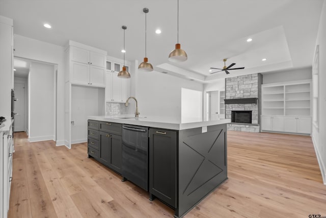 kitchen with built in shelves, sink, decorative light fixtures, white cabinets, and a stone fireplace