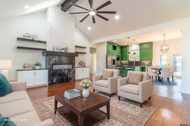 living room featuring ceiling fan, high vaulted ceiling, a fireplace, and light hardwood / wood-style floors