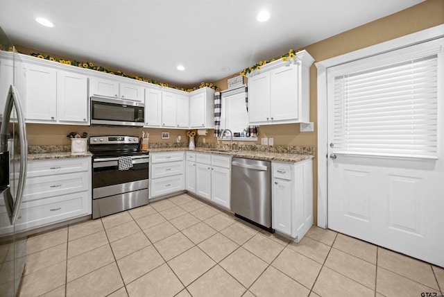 kitchen with white cabinetry, light tile patterned floors, stainless steel appliances, and light stone counters