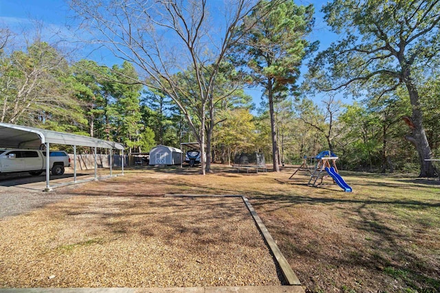 view of yard with a carport, a shed, and a playground