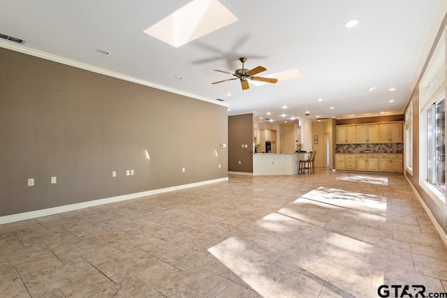 unfurnished living room featuring a skylight, ceiling fan, and crown molding