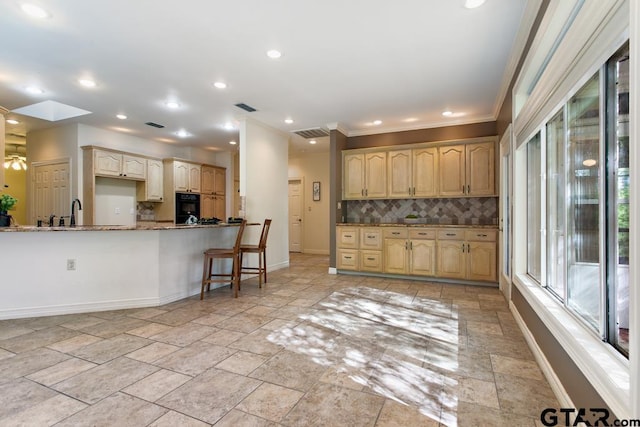 kitchen featuring tasteful backsplash, a skylight, light stone counters, crown molding, and black oven