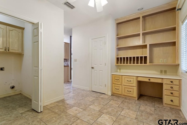 unfurnished office featuring a wealth of natural light, built in desk, and ceiling fan