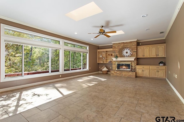 unfurnished living room with a brick fireplace, ceiling fan, crown molding, and a skylight