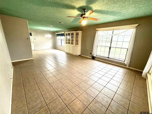 unfurnished living room featuring a textured ceiling, ceiling fan, and light tile patterned flooring