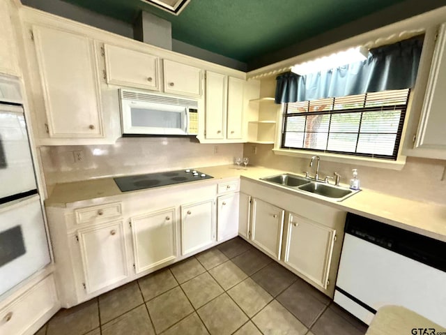 kitchen featuring backsplash, tile patterned floors, white appliances, sink, and white cabinets