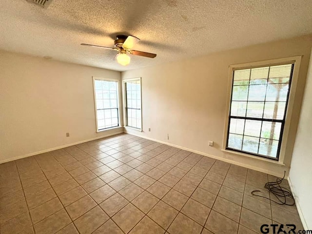 spare room featuring ceiling fan, light tile patterned floors, and a textured ceiling