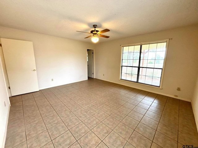 unfurnished room with ceiling fan, light tile patterned floors, and a textured ceiling