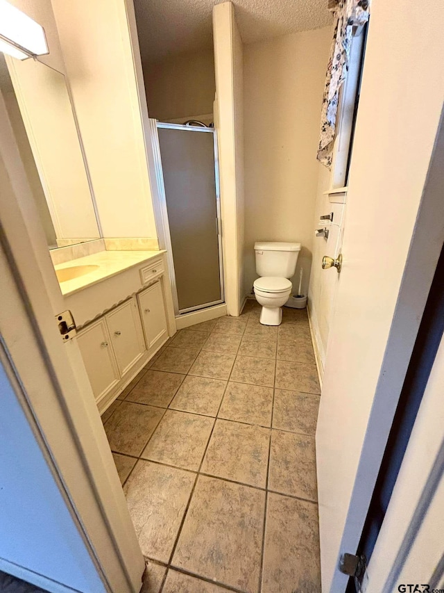 bathroom with vanity, a shower with door, tile patterned flooring, toilet, and a textured ceiling