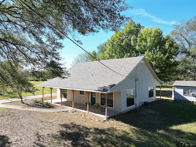 rear view of property featuring a lawn, central AC, and a patio