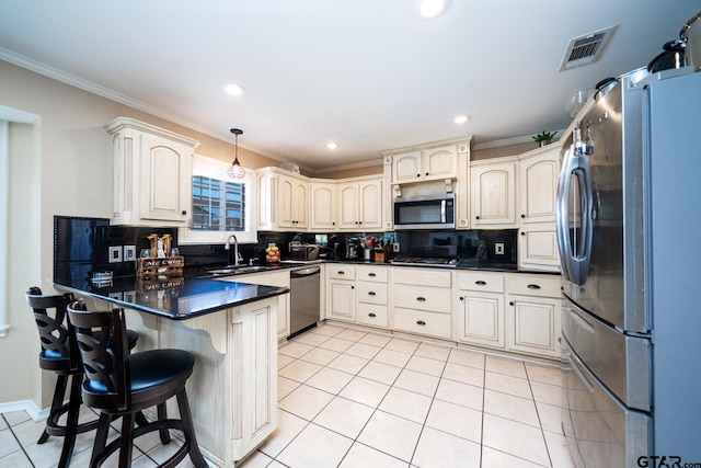 kitchen with appliances with stainless steel finishes, hanging light fixtures, sink, decorative backsplash, and kitchen peninsula