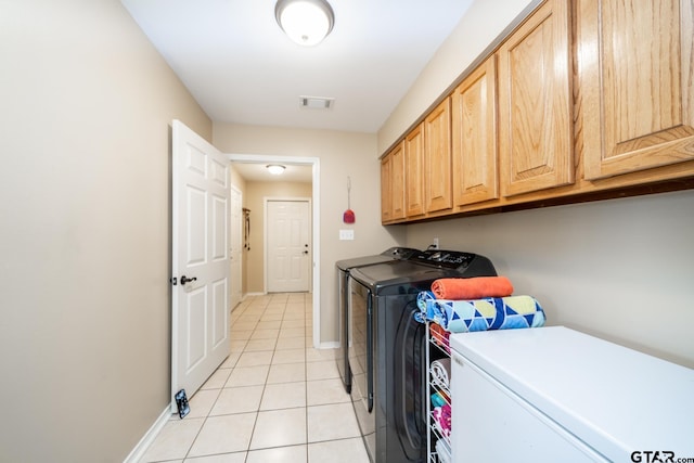 washroom featuring washing machine and clothes dryer, cabinets, and light tile patterned floors