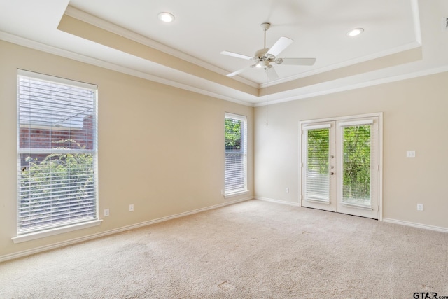 carpeted empty room featuring ornamental molding, baseboards, a raised ceiling, and a ceiling fan