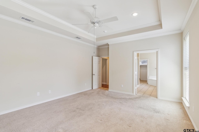 unfurnished bedroom with a raised ceiling, light colored carpet, ornamental molding, and visible vents