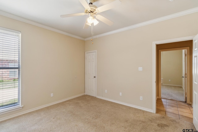 spare room with ornamental molding, baseboards, a ceiling fan, and light colored carpet