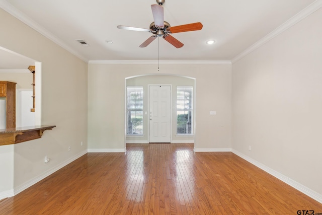 unfurnished room featuring arched walkways, visible vents, ornamental molding, and light wood-style flooring