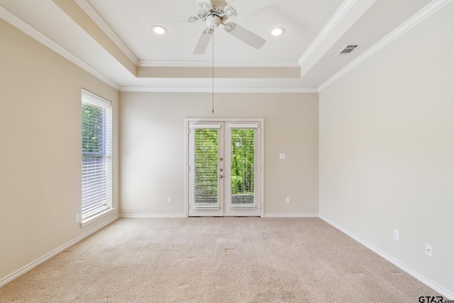 empty room with crown molding, visible vents, ceiling fan, and a raised ceiling