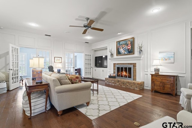 5807 Stoneleigh Dr, Tyler, TX 75703 - living room with a decorative wall, a ceiling fan, crown molding, a fireplace, and dark wood-type flooring