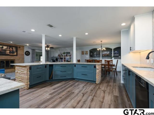 kitchen with sink, a fireplace, dishwasher, ceiling fan with notable chandelier, and blue cabinetry