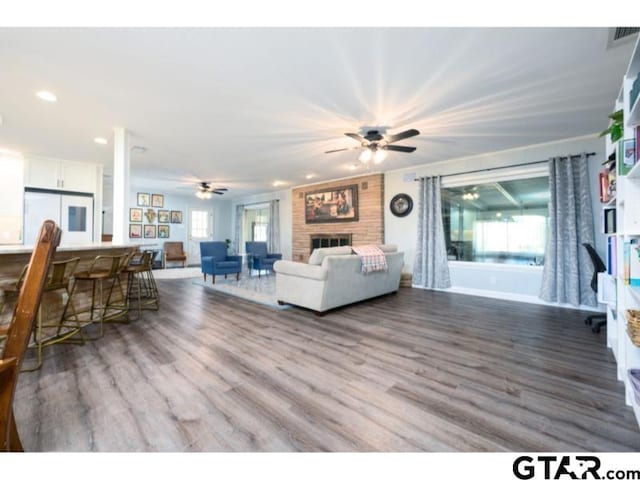 living room with ceiling fan, a fireplace, hardwood / wood-style floors, and a wealth of natural light