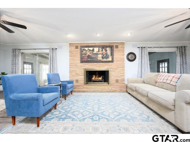 living room with wood-type flooring, a fireplace, ceiling fan, and ornamental molding