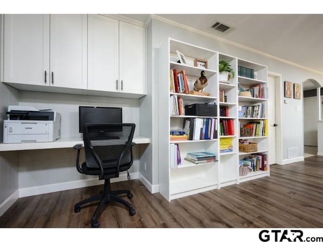 office with built in desk, crown molding, and dark wood-type flooring