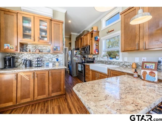 kitchen with light stone countertops, backsplash, appliances with stainless steel finishes, ornamental molding, and sink