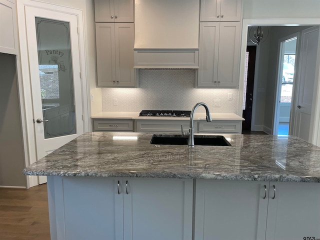 kitchen featuring gray cabinetry, sink, dark wood-type flooring, dark stone countertops, and decorative backsplash