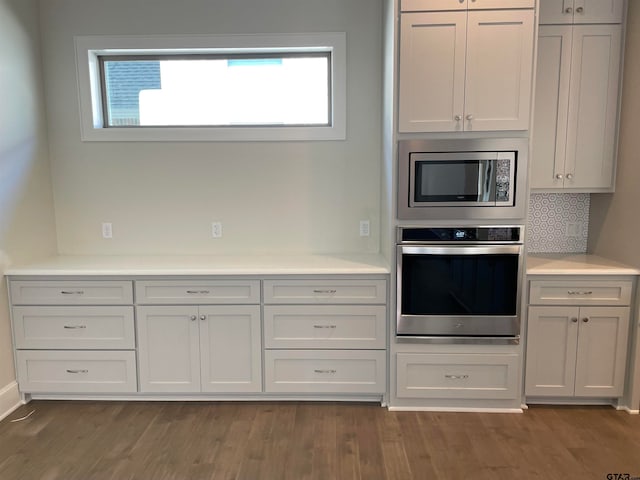 kitchen with white cabinets, dark hardwood / wood-style flooring, appliances with stainless steel finishes, and tasteful backsplash