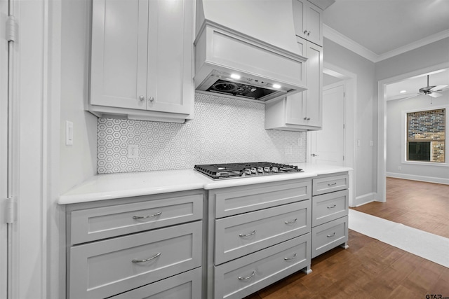 kitchen featuring gray cabinetry, stainless steel gas stovetop, premium range hood, and backsplash