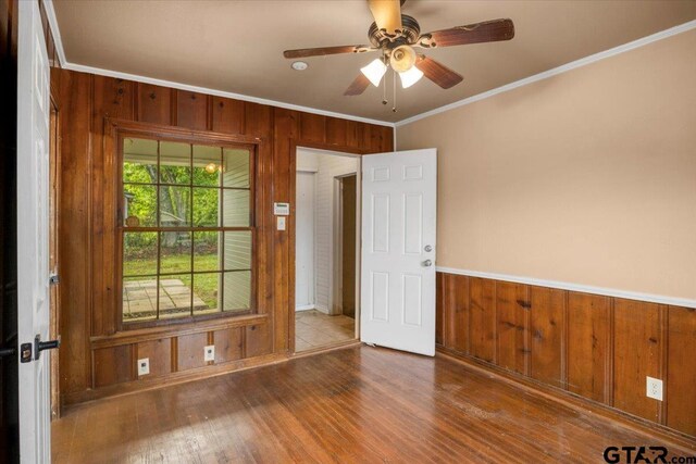 1330 Graham Dr, Tyler, TX 75701 - empty room with ornamental molding, wood walls, a ceiling fan, and wood finished floors