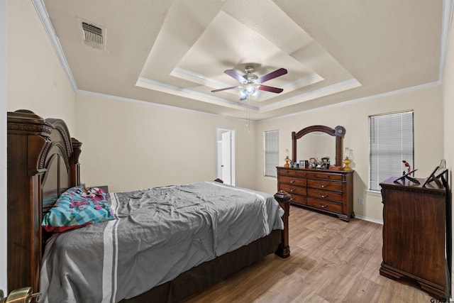 bedroom with ceiling fan, a raised ceiling, light hardwood / wood-style flooring, and ornamental molding