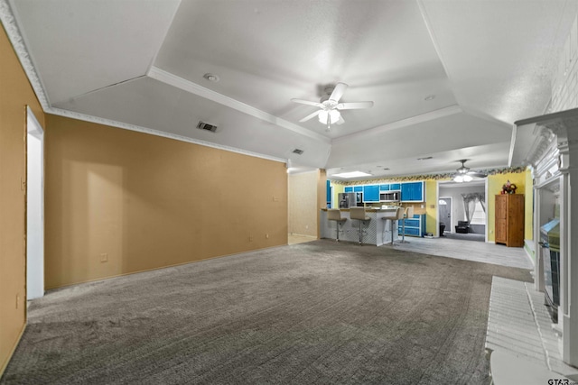 unfurnished living room featuring ceiling fan, light colored carpet, and ornamental molding