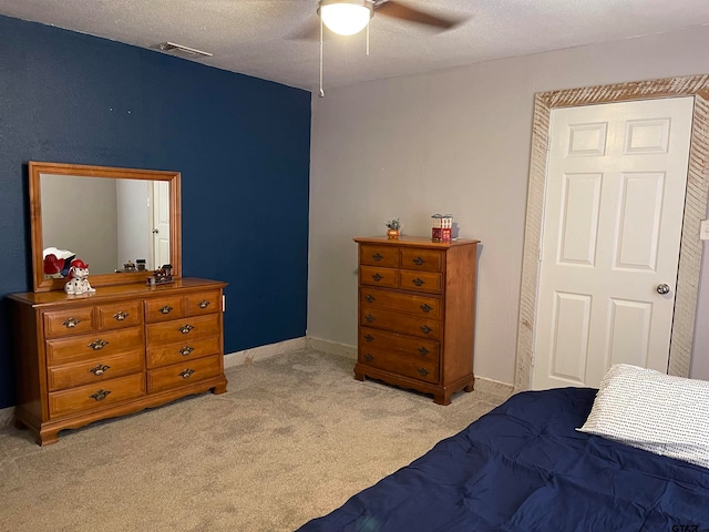 carpeted bedroom featuring ceiling fan and a textured ceiling